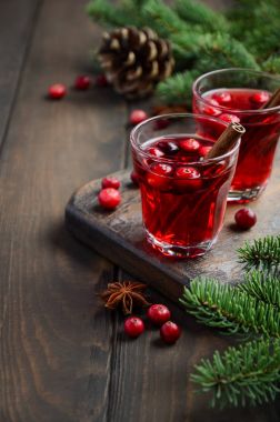 Kızılcık içki çam dalları, baharat ve taze çilek ile dekore edilmiş ahşap arka plan üzerinde.