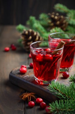 Kızılcık içki çam dalları, baharat ve taze çilek ile dekore edilmiş ahşap arka plan üzerinde.