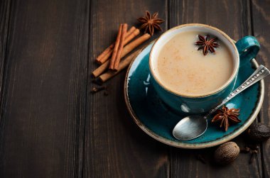 Hint masala chai çay. Koyu ahşap zemin üzerine sütlü baharatlı çay.