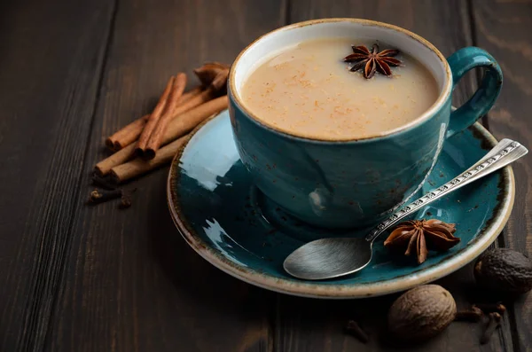 Indický masala chai čaj. Kořeněný čaj s mlékem na tmavé dřevěné pozadí. — Stock fotografie