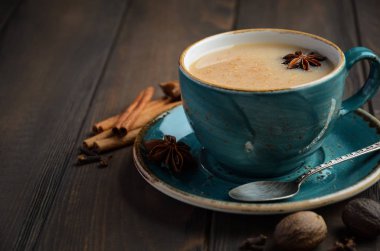 Hint masala chai çay. Koyu ahşap zemin üzerine sütlü baharatlı çay.