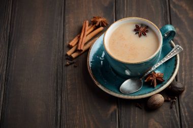 Hint masala chai çay. Koyu ahşap zemin üzerine sütlü baharatlı çay.