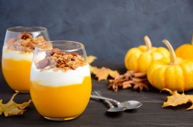 Yoğurt ve koyu ahşap masa üzerinde ev yapımı granola ile kabak tatlısı.