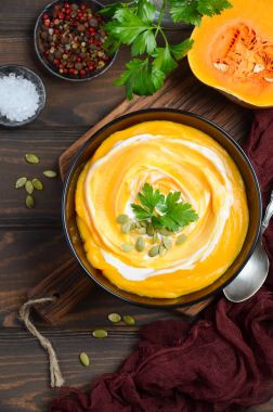 Ahşap arka plan üzerinde krem ve kabak çekirdeği ile kabak kremalı çorba.