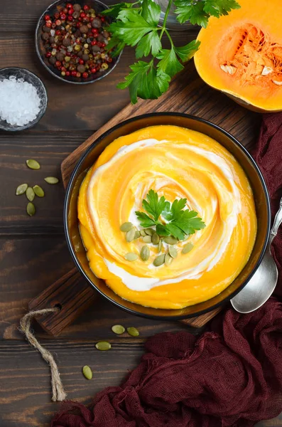 Ahşap arka plan üzerinde krem ve kabak çekirdeği ile kabak kremalı çorba.