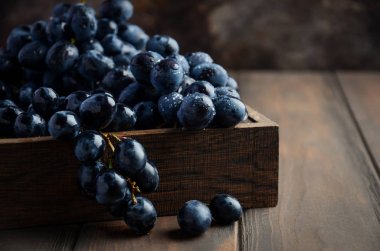 Koyu ahşap tepsi ahşap masa üzerinde taze siyah üzüm