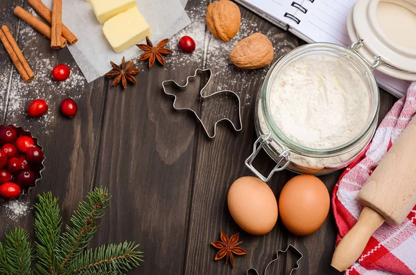 Різдвяні інгредієнти випічки - різаки для печива, спеції, масло, яйця та борошно на темному дерев'яному фоні — стокове фото
