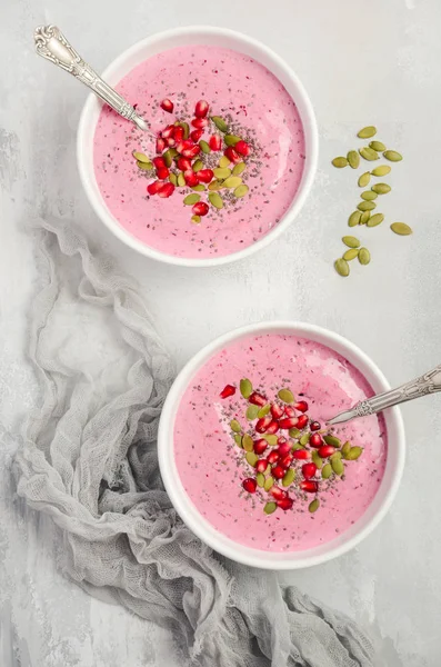 Smoothie bowl with chia seeds, pumpkin seeds and pomegranate for healthy vegan vegetarian diet breakfast, top view, flat lay.