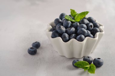 Olgun tatlı yaban mersini seçici odak, bir gri beton zemin üzerine beyaz kase alanı Kopyala.