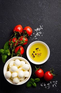 İtalyan yemeği malzemeler Mozzarella peyniri, domates, fesleğen ve siyah arka plan, üstten görünüm, üzerine zeytinyağı lay düz.