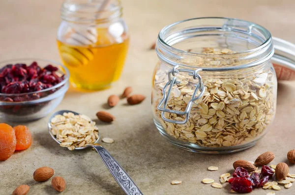 Ingredients for homemade oatmeal granola. Oat flakes, honey, almond nuts, dried cranberries and apricots. Healthy breakfast concept.