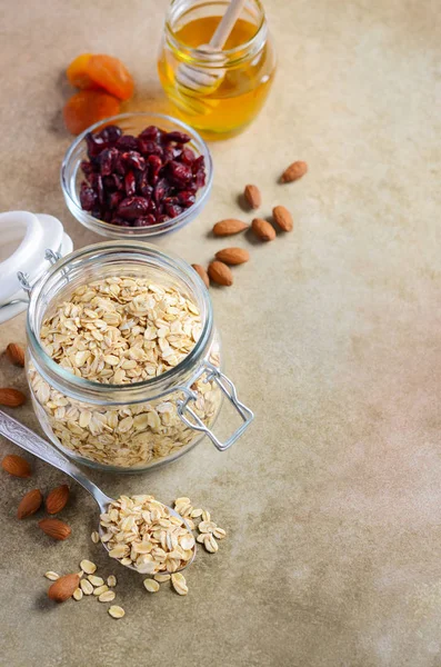 Ingredients for homemade oatmeal granola. Oat flakes, honey, almond nuts, dried cranberries and apricots. Healthy breakfast concept.