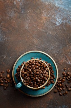 Doğal organik kahve çekirdekleri koyu paslı arka plan, üstten görünüm, düz lay, kopya alanı üzerinde mavi Kupası'nda kavrulmuş.