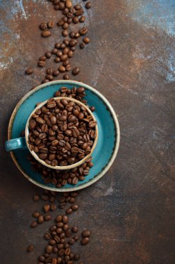 Doğal organik kahve çekirdekleri koyu paslı arka plan, üstten görünüm, düz lay, kopya alanı üzerinde mavi Kupası'nda kavrulmuş.