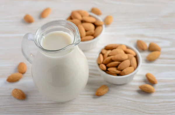 Almond milk and almonds on a white wooden background, selective focus.