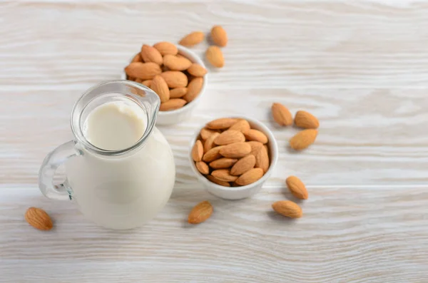 Almond milk and almonds on a white wooden background, selective focus.