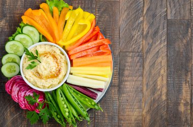 Humus tabağı ve çeşitli sebze atıştırmalıkları. Sağlıklı vejetaryen ve vejetaryen yemekleri. Üst görünüm, düz görünüm, kopyalama alanı.