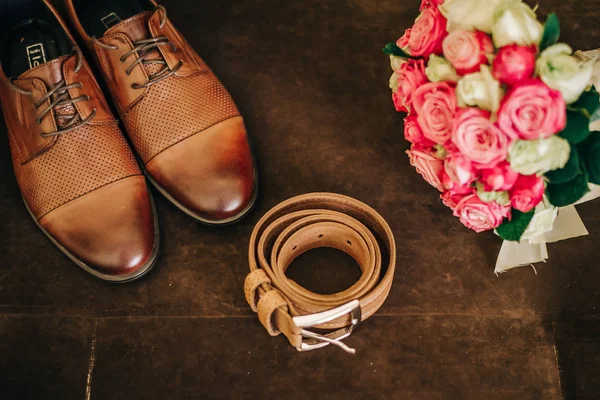 brown groom shoes with a belt and a bouquet of flowers