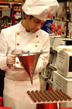 Roma, İtalya - 26 Ekim 2019: Lindt mağazasında çikolata dolgulu pralinler ile doldurulan genç işçi. Lindt & Sprungli Ag, İsviçreli bir çikolata ve şekerleme şirketidir.