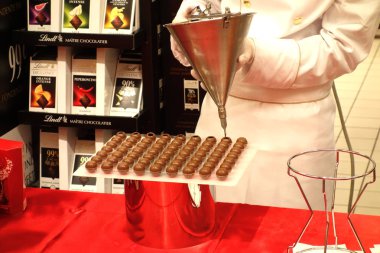 Roma, İtalya - 26 Ekim 2019: Lindt mağazasında çikolata dolgulu pralinler ile doldurulan genç işçi. Lindt & Sprungli Ag, İsviçreli bir çikolata ve şekerleme şirketidir.
