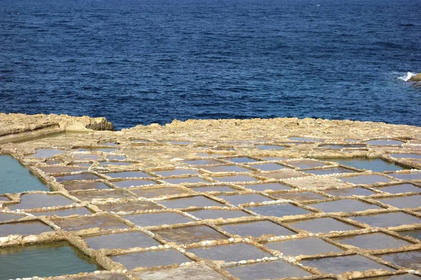 Salt pans or salt flats in Xwejni, Zebbug, Gozo, Malta, longtime locale for salt production, featuring salt pans in geometric patterns by the ocean