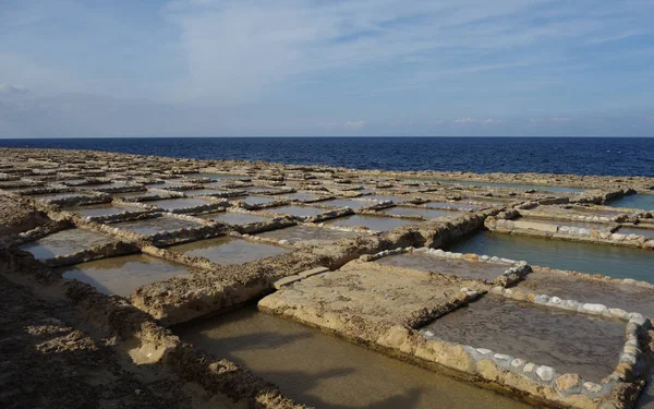 Salt pans or salt flats in Xwejni, Zebbug, Gozo, Malta, longtime locale for salt production, featuring salt pans in geometric patterns by the ocean