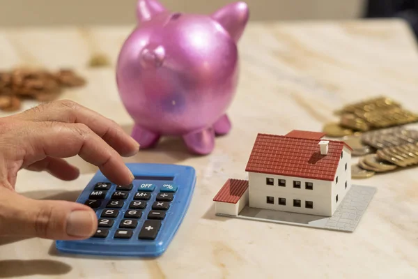 Dreaming a new home concept. Calculating savings, model house and piggy bank