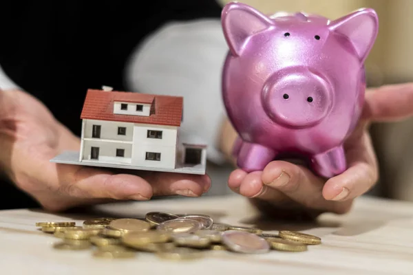 Saving money and dreaming a new home concept. Coins, model house and piggy bank. Selective focus