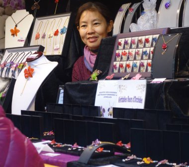 Brüksel, Belçika - 24 Aralık 2019: Gerçek orkide çiçeklerinden yapılmış bijou satan Asyalı kadın