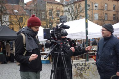 Brüksel, Belçika - 26 Aralık 2019: Açık havada çalışan gazeteci ve kameraman bir adamla röportaj yapıyor