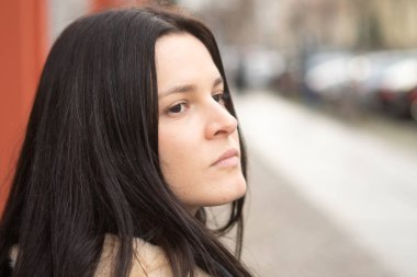 Düşünceli, genç ve esmer bir kadının yarım portresi.