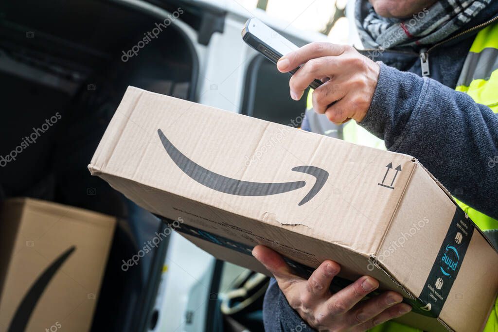 Berlin, Germany - January 27, 2020: Cropped shot of an Amazon Prime delivery agent scanning barcodes on boxes during his work shift. Amazon is an American electronic online commerce company