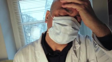 Coronavirus salgını enfeksiyonunu önlemek için maske takan kafası karışmış ya da enfekte olmuş bir doktor. Yavaş çekim