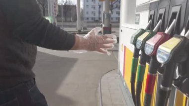 Berlin, Germany - February 29, 2020: Unrecognizable man holding a fuel pump nozzle choosing from different kinds of fuel in a filling station