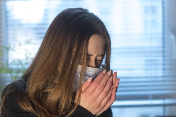 Prevent the spread of the Coronavirus Disease 2019 (COVID-19). Young woman sneezing or coughing in a protective medical face mask