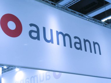Berlin, Germany - June 21, 2018: Sign of the German company Aumann Espelkamp GmbH, machine manufacturer for the automotive sector with a focus on the future market of e-mobility clipart
