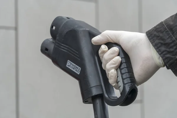 德国柏林 2020年3月31日 男子手拿手套 手持凤凰号接触式电动车充电连接器 在眼镜蛇 19爆发期间防止细菌和大肠埃希菌 — 图库照片