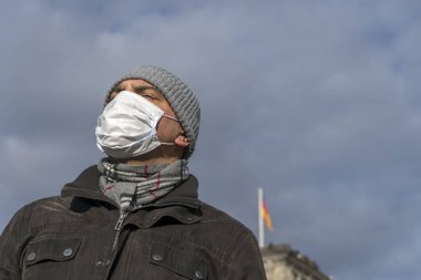Şehrin tecridi sırasında Berlin Reichstag binasının önünde tek başına poz veren yetişkin bir adam yüzüne koruyucu maske takıyor.