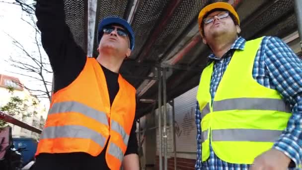 Två Ingenjörer Hårdhatt Och Reflekterande Skyddsvästar Pratar Byggarbetsplatsen — Stockvideo