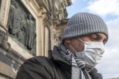 Hastalık salgını, COVID-19 Coronavirus SARS-CoV-2 salgını. Burnunu ve ağzını dışarıda otururken korumak için yüzünü tıbbi maskeyle kapatan bir adamın profil portresi.