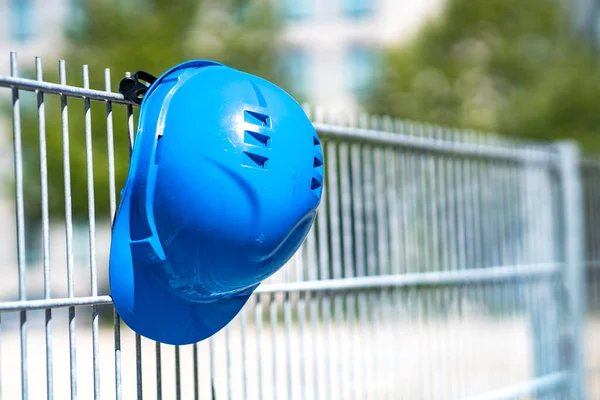 Occupational safety and safety gear. Blue hard hat hanging on scaffolding. Focus on foreground