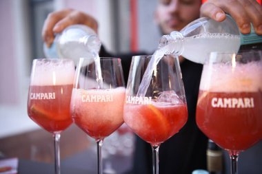 Berlin, Almanya - 19 Haziran 2019: Spritz kokteyl aperatifini hazırlamak, Campari likörü ve ros şarabını veya Prosecco 'yu buz ve limon tekerleriyle dolu bardaklara doldurmak
