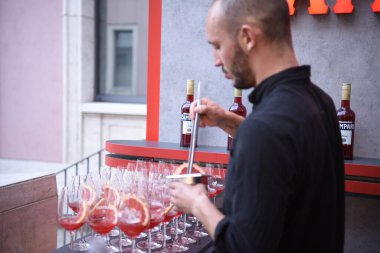 Berlin, Almanya - 19 Haziran 2019: Barmen veya barmen Spritz kokteyl aperatifi hazırlıyor, Campari likörü ve ros şarabı veya kovboyları buz ve greyfurt tekerleği dolu bardaklara dolduruyor