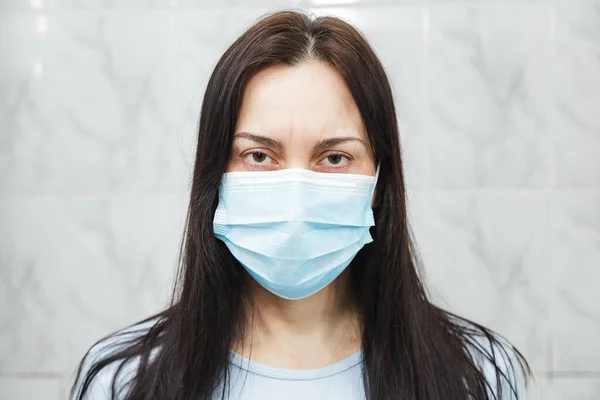Muayenehanedeki karantina altındaki kadın mavi koruyucu maske takıyor.
