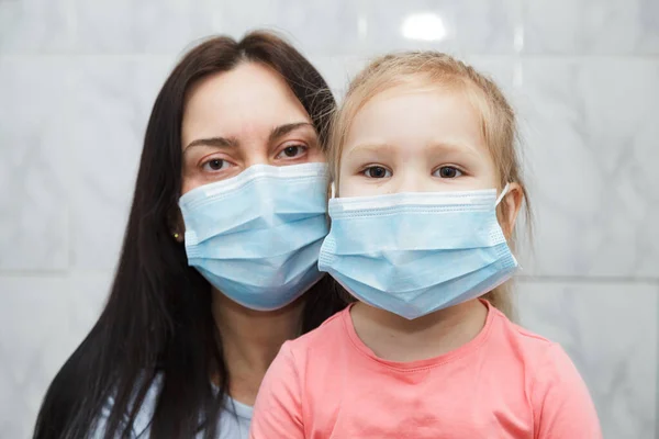 Quarantined woman and child in medical masks. Baby in the focus.