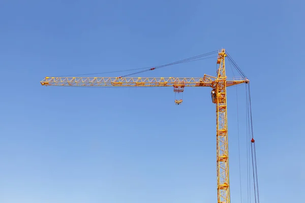 Yellow Construction Tower Crane Against Blue Sky.