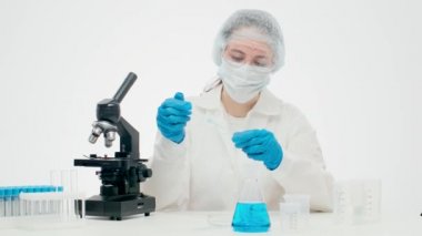 Genç kadın bilim adamı cam şişede yeni bir ilacı inceliyor.