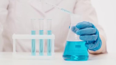 Fen laboratuarında çalışan bir kadının elleri pipet analizi yaptırır.
