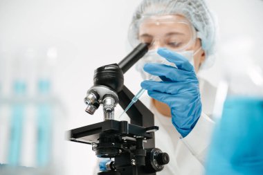 Laboratuvarda koronavirüs testi yapmak için eldiven damlatma reaktörü kullanan tıbbi personel.