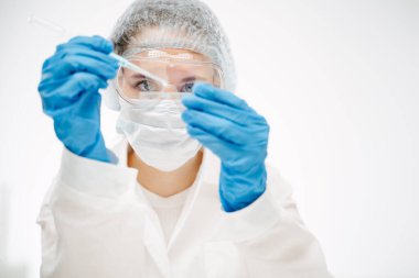 Koruyucu giyimde genç asistan özel reaksiyonla koronavirüs testi yapıyor.